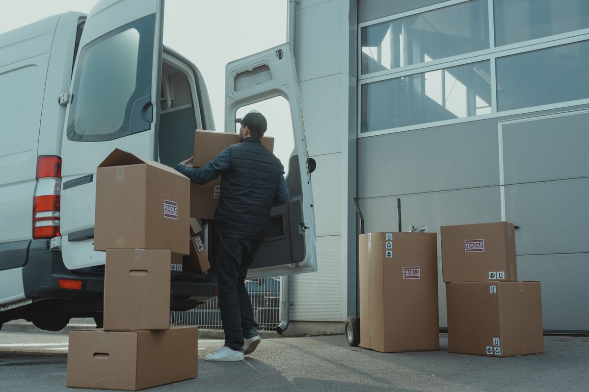 Logistiek medewerker laadt goederen in een bestelwagen.